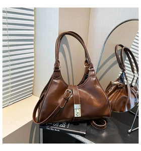 Détail du sac à main marron brillant avec fermoir rotatif doré et deux longues anses
