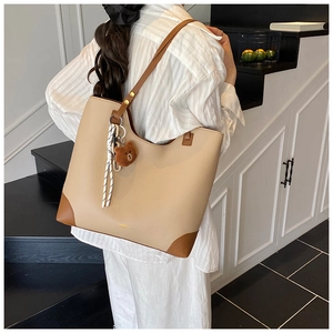 Lifestyle view of apricot textured leather tote bag with brown straps and bear pendant