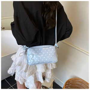 Détail d'un sac à bandoulière bleu clair à pois avec perles et foulard en soie décoratif