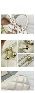 Detail of beige quilted leather bag with gold ball zipper and patterned silk scarf wrap