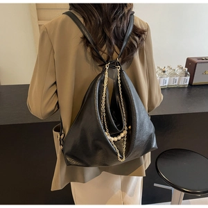 Close-up of black PU leather bag with golden chains and elegant pearl strap details