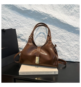 Gros plan d'un sac en cuir marron brillant avec fermoir doré sur fond de livre d'art