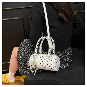 Détail du sac cylindre blanc à pois avec franges en perles et pendentif coeur