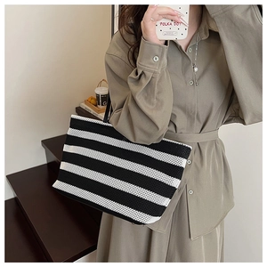 Détail d'un sac cabas tissé à rayures noires et blanches avec fines bandoulières