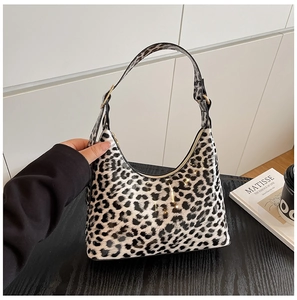 Detailed view of trendy black and white leopard print underarm bag on a wooden table
