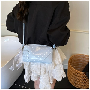 Détail du sac bandoulière bleu clair à pois avec couture B et ruban perle sur mannequin
