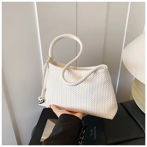 Detail view of cream woven bucket bag with heart pendant and leather handle for women