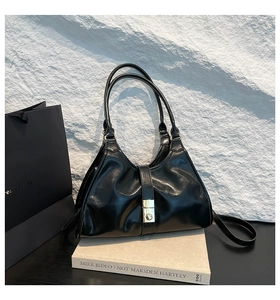Détail d'un sac à main en cuir noir brillant avec boucle en métal doré et base épurée