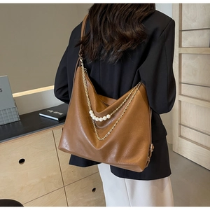 Detail of a brown leather hobo bag featuring elegant pearl and gold chain decorations