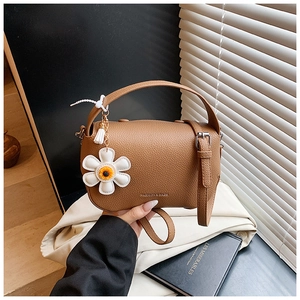 Close-up of brown lychee pattern leather bag with daisy charm and fashion logo