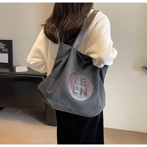 Close-up of canvas tote bag showing the brown leather patch with embossed logo and texture