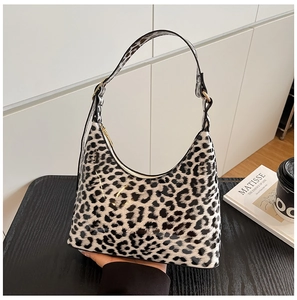 Detail of glossy black and white leopard print hobo bag with gold metal hardware