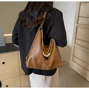 Brown faux leather bucket bag detail with elegant metal chain and pearl decorations