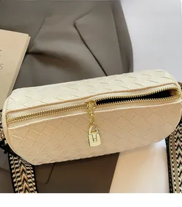 Close-up of woven cream cylinder bag with gold zipper and geometric fabric strap