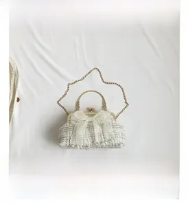 Detail van witte tweed avondtas met organza strik parelaccenten en goudkleurig handvat