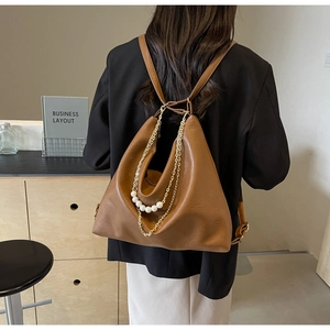 Detail of brown PU leather tote with elegant gold chains and white pearl embellishments