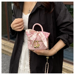 Pink quilted bucket bag with floral scarf handle and chain strap shown on a model