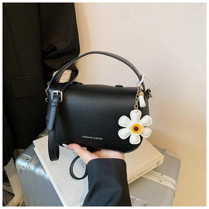 Detail of black lychee leather handbag with white daisy charm and silver clasp