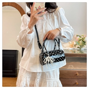 Détail d'un sac cylindrique à pois avec un pendentif décoratif en perles et nœud