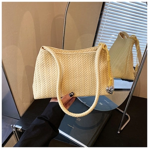 Close-up of beige woven texture handbag with a heart-shaped silver pendant detail