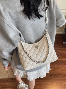 Sac bandoulière matelassé blanc cassé avec strass et boucle étoile porté par un mannequin