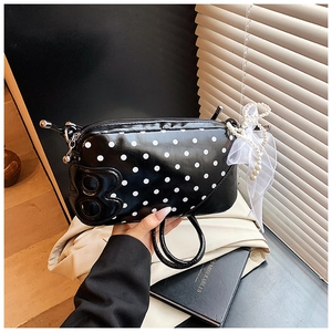Gros plan détaillé d'un sac à main noir à pois avec breloque perle et nœud en dentelle