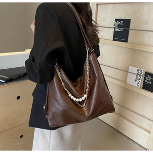 Detailed shot of dark brown tote with vintage texture, gold chain and pearl accents