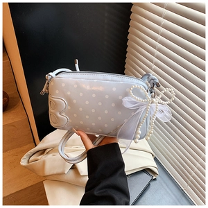 Gros plan du sac bleu clair à pois avec la lettre B et nœud en perles élégant
