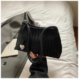 Detail of woven black hobo bag with thick handle and silver heart charm decoration