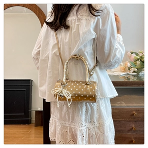 Détail du sac cylindrique doré métallisé à pois avec breloque nœud en perles chic