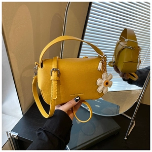 Detail of yellow lychee texture leather bag with daisy charm and silver metal hardware