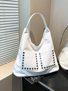 White hobo shoulder bag with silver studs and front pockets in a lifestyle setting