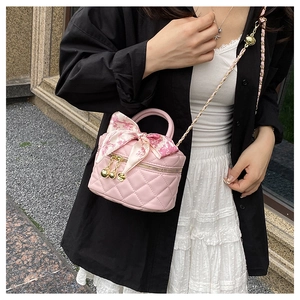 Detail of pink quilted mini bag featuring golden ball tassel and floral bow accessory