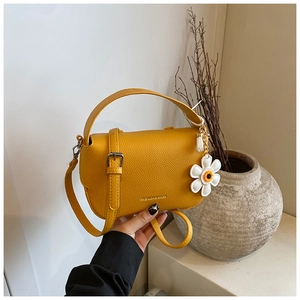 Detail of yellow lychee pattern leather bag with daisy charm and fashion text print