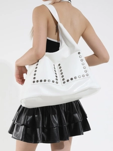 White hobo shoulder bag with silver rivet details shown on model in minimalist setting