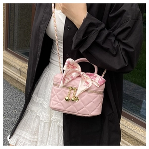 Close-up of pink quilted mini bag with floral scarf handle and gold chain strap details