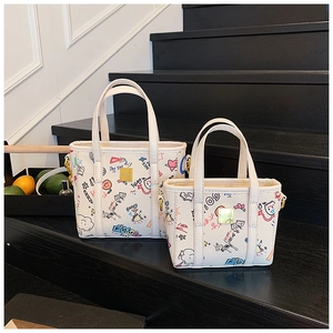 Detail of printed bucket bags with gold logo and colorful graffiti on white background