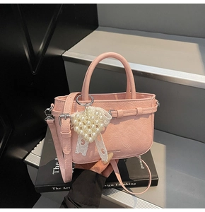 Detail der rosa PU-Lederhandtasche mit Plissee-Struktur und Herz-Perlenanhänger als Accessoire
