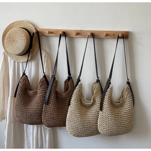 Detail of hand-woven straw tote bags with leather straps hanging in a summer setting