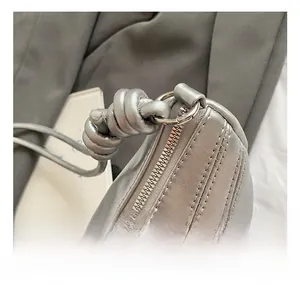 Vue macro du sac métallisé argenté avec poignée nouée et détails en métal de qualité