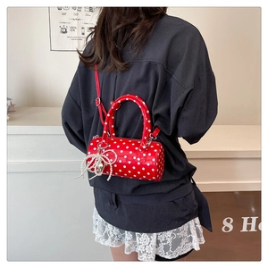 Détail du sac cylindrique rouge à pois avec breloque nœud en perles et bandoulière