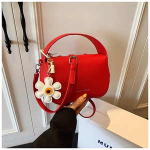 Detail of red lychee leather handbag with golden text and white sunflower charm