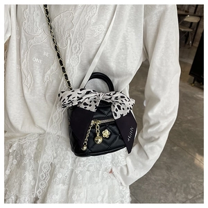 Close-up of quilted mini crossbody bag with gold chain and camellia flower charm
