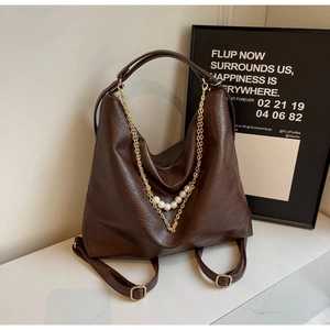 Detail of dark brown leather bag with golden chain and pearl decorative strap