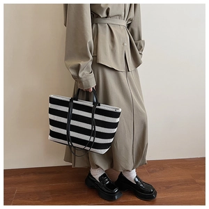 Détail d'un grand sac cabas à rayures noires et blanches avec de longues anses noires