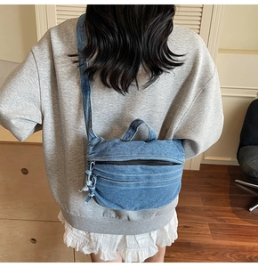 Model view showing the blue denim crossbody bag worn on the back in a cozy indoor setting