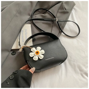 Detail of black lychee leather crossbody bag with daisy charm and fashion lettering