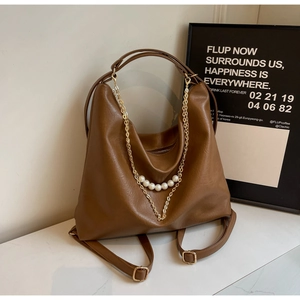 Close-up of brown leather bag with elegant gold chains and pearl bead accents