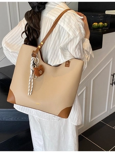 Large beige leather tote bag with dark brown trim and cute bear charm for daily commute