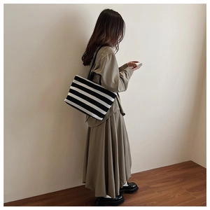Vue détaillée du grand sac cabas à rayures avec lanières en cuir noir et texture tissée